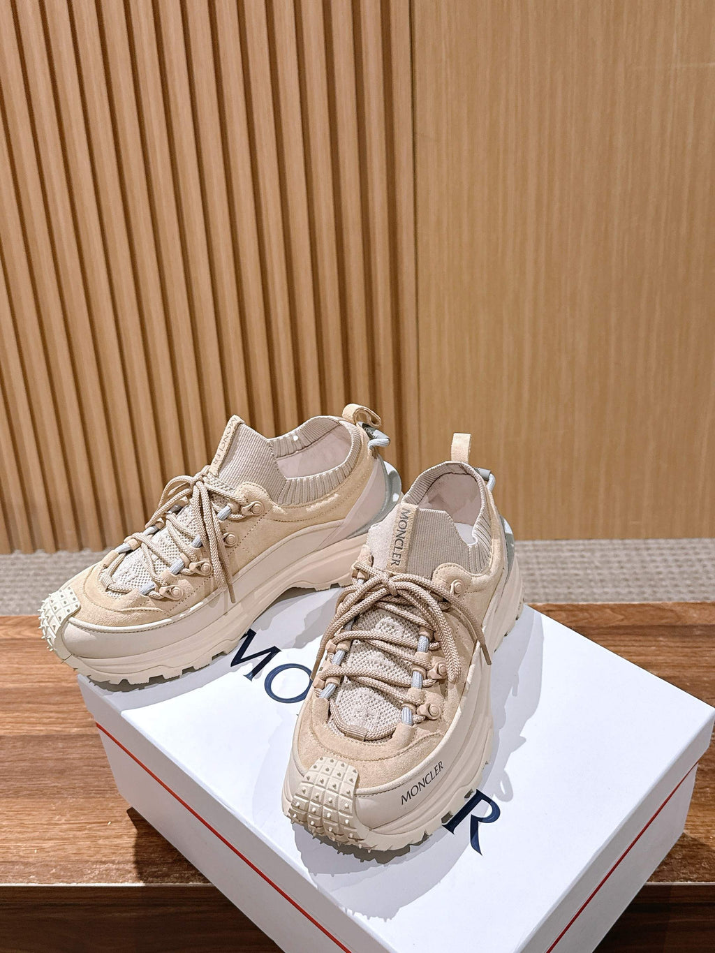 Moncler beige lace-up sneakers with chunky soles, angled view on boxes.