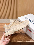 Moncler beige lace-up sneaker held in hand, side profile with rugged sole.