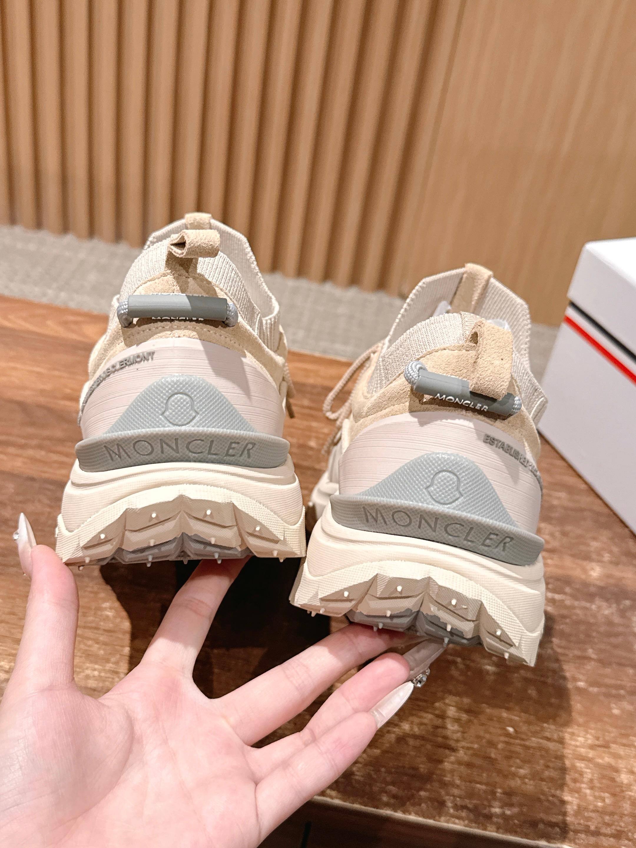 Moncler beige sneakers shown from the heel, with strap and logo detail.