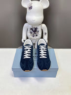 Prada unisex suede sneakers, dark blue, white laces and rubber sole on box.