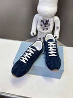 Prada unisex suede sneakers, dark blue, white laces, visible side branding on box.