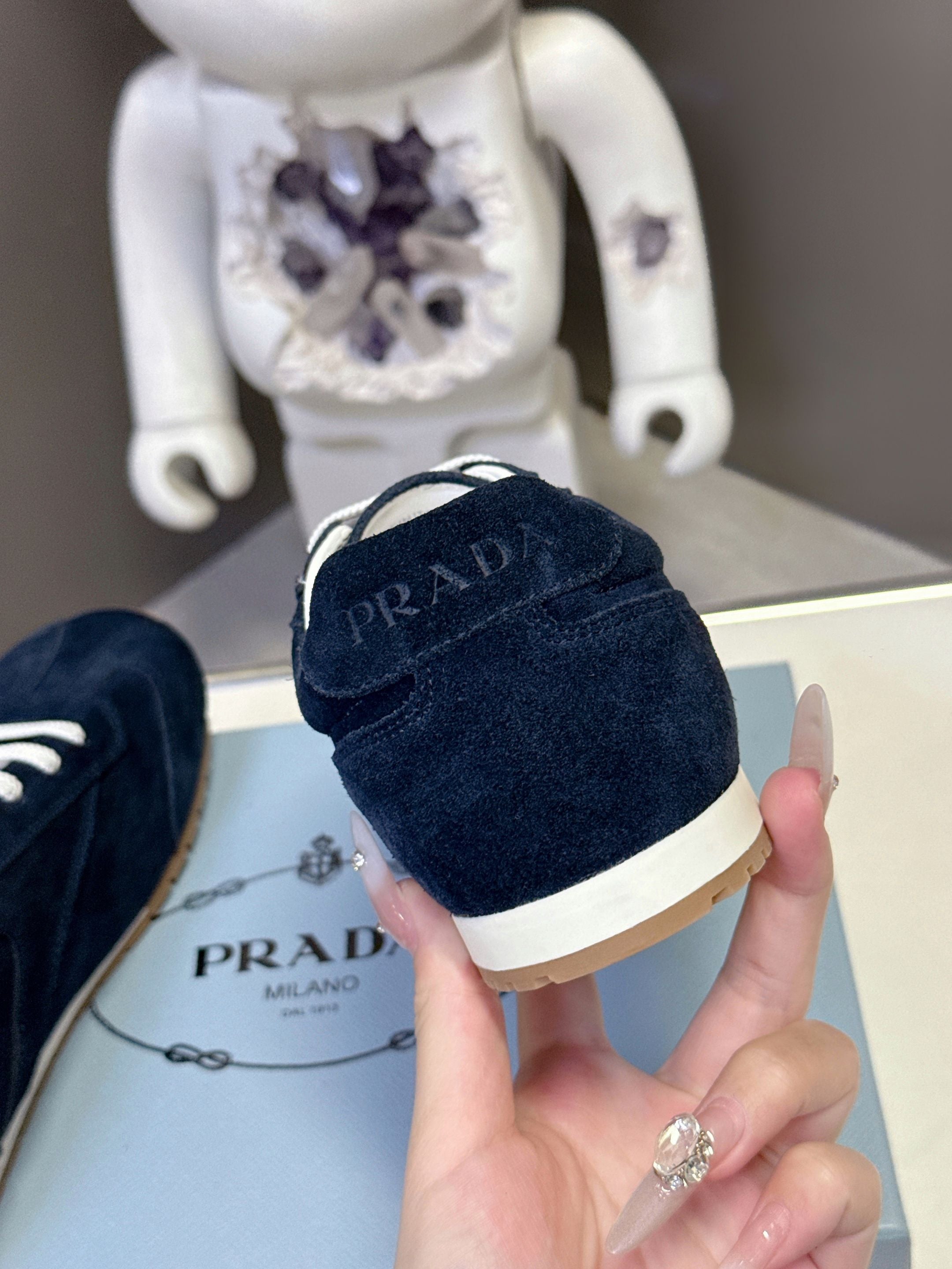 Prada dark blue suede sneakers with white lace-up, gum sole and heel logo.