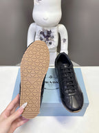 Black leather lace-up sneaker showing tan textured outsole and stitched upper