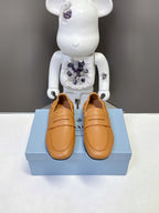 Prada tan leather loafers with strap detail, rounded toe, and low sole