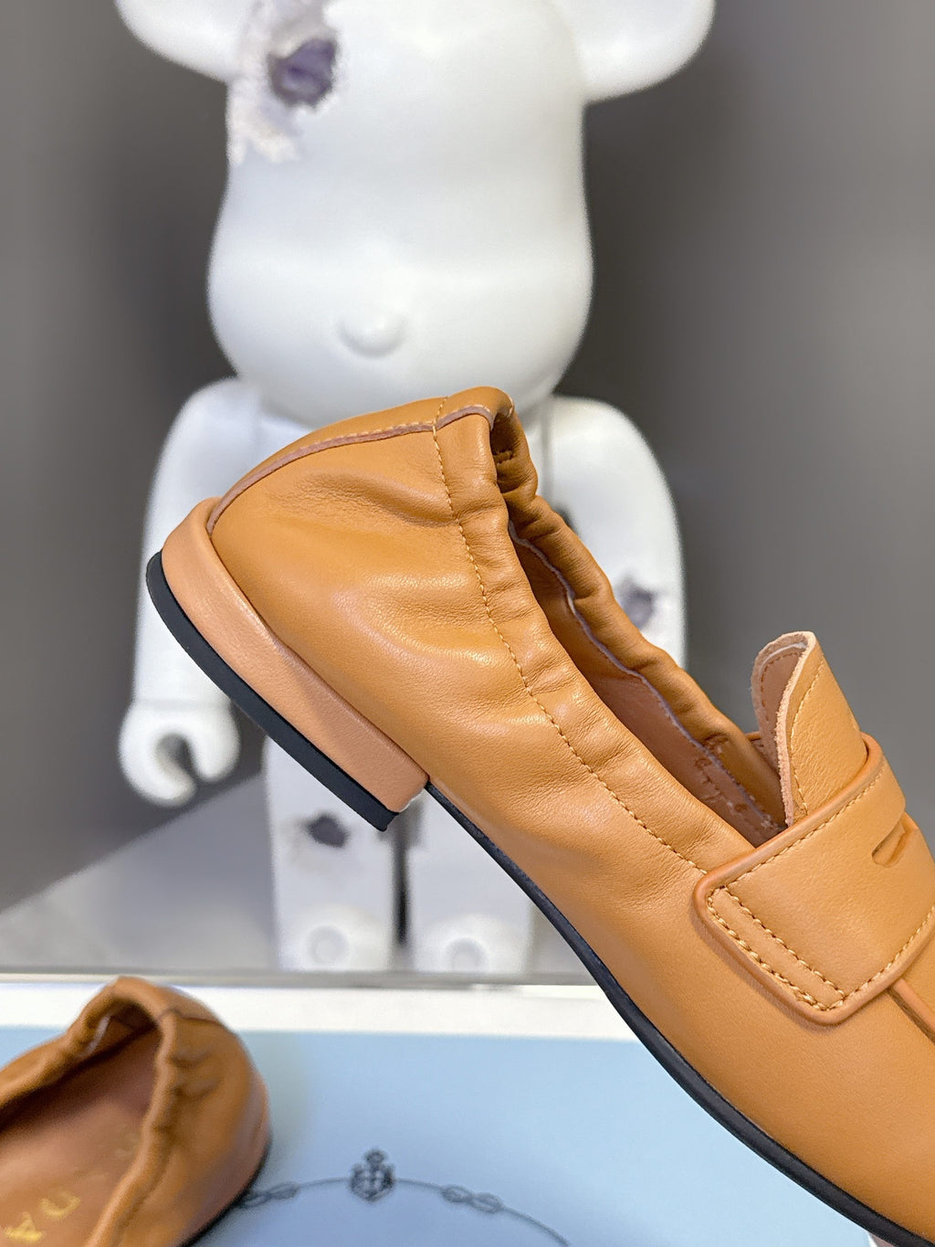 Prada tan leather loafer with strap detail and black rubber sole edge