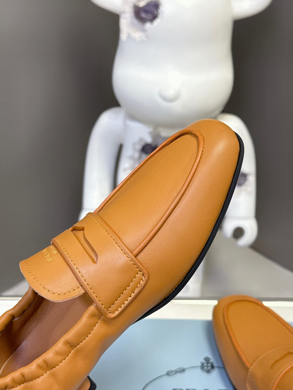 Prada tan leather loafer side profile with strap and low black sole