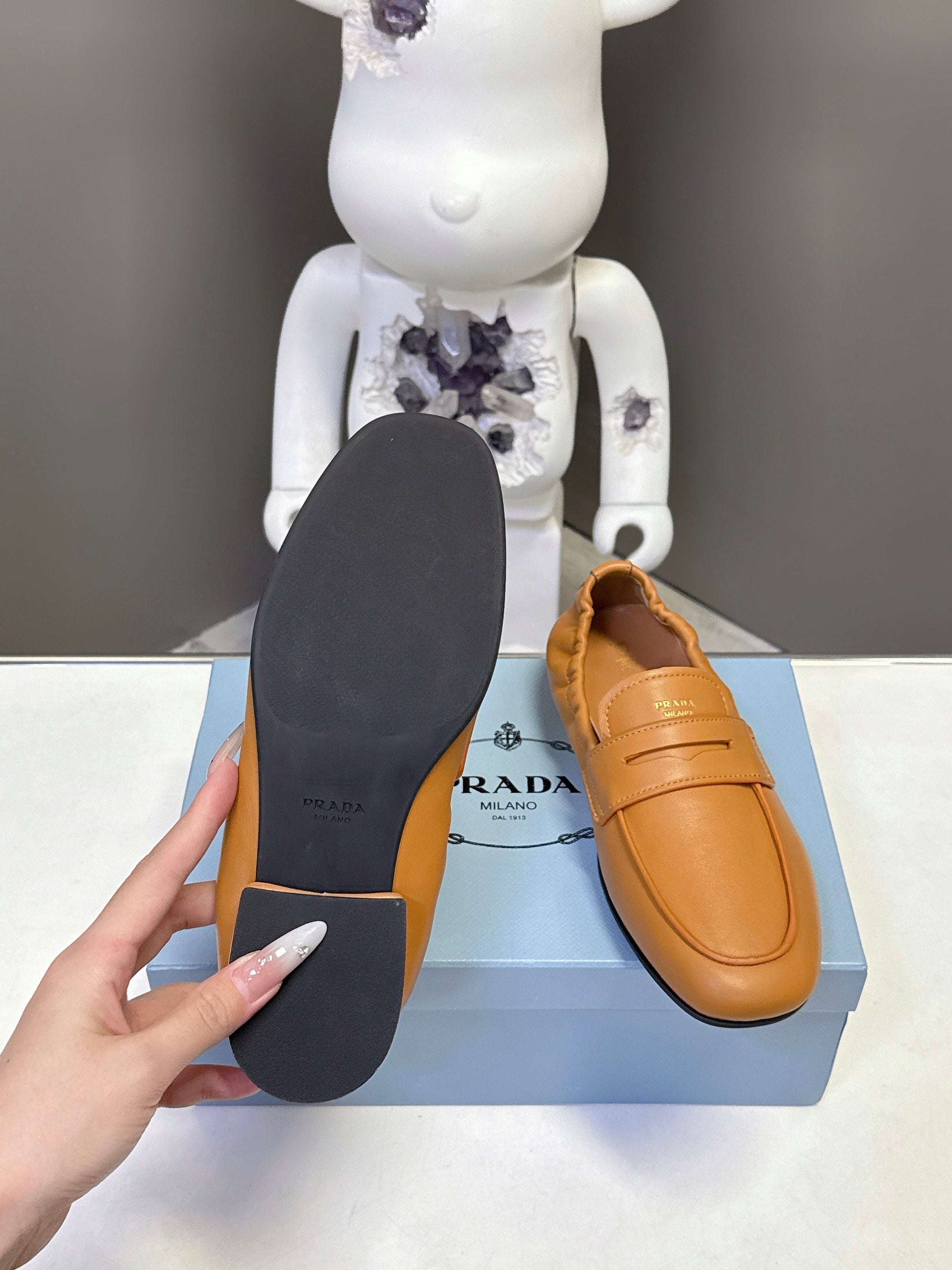 Prada tan leather loafers showing dark rubber outsole and heel underside