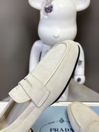 Prada suede loafer side view, light beige with strap detail and black sole edge
