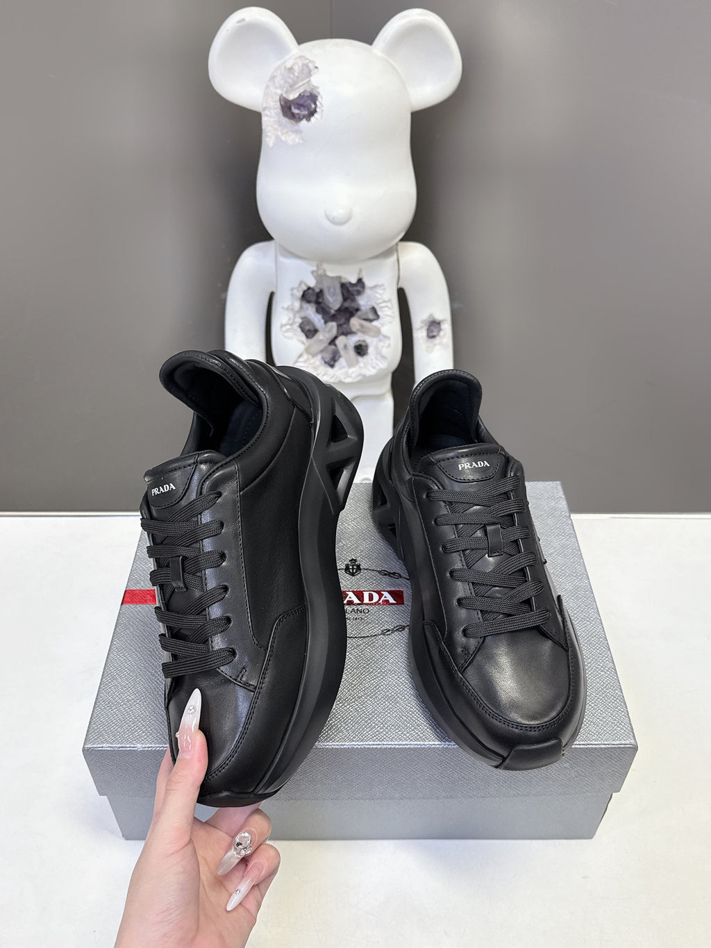 Prada unisex sneakers, black side view with lace-up and embossed logo panel