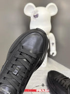 Prada unisex sneakers, black lace-up front view with patterned stitching