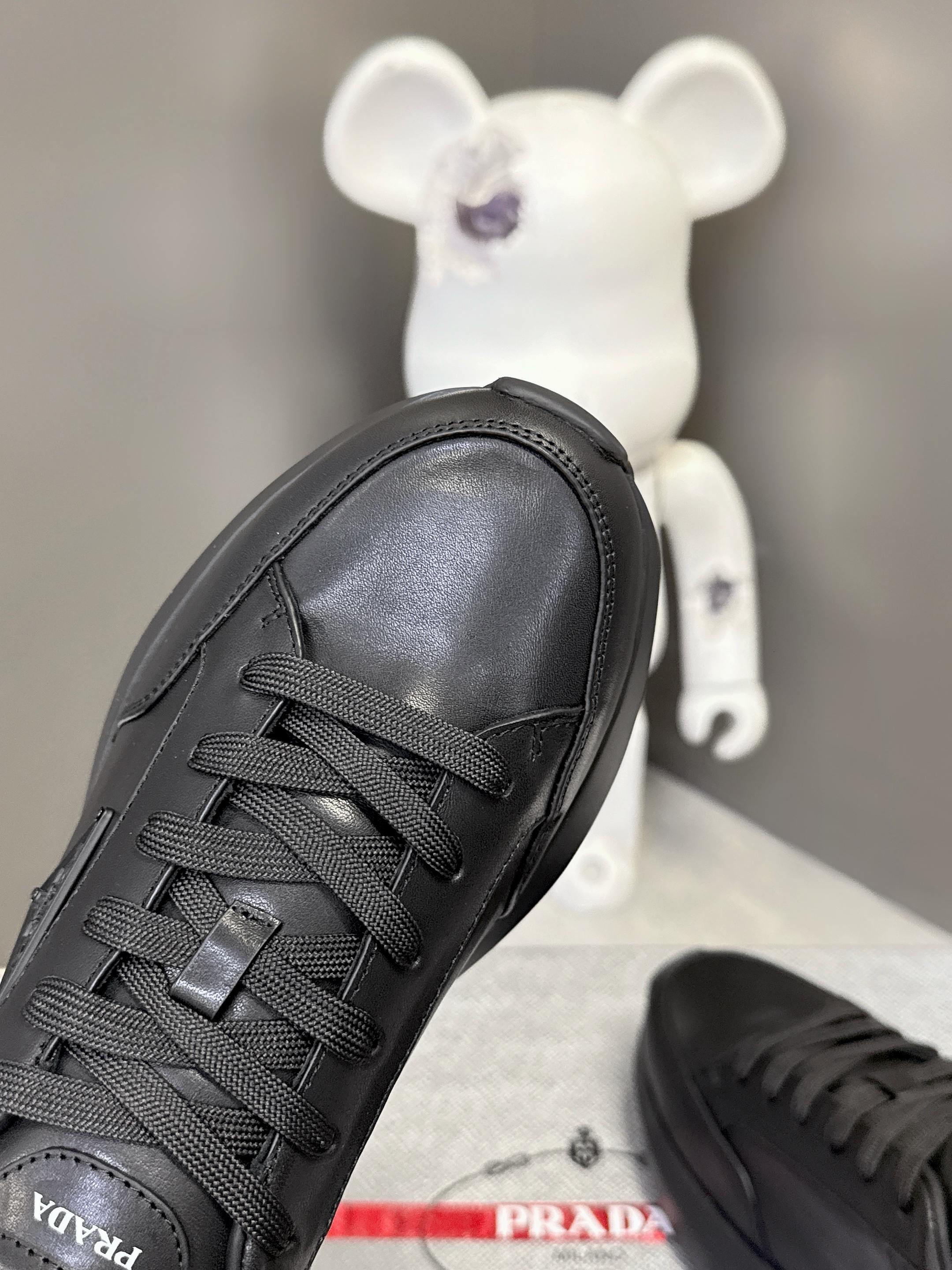 Prada unisex sneakers, black lace-up front view with patterned stitching