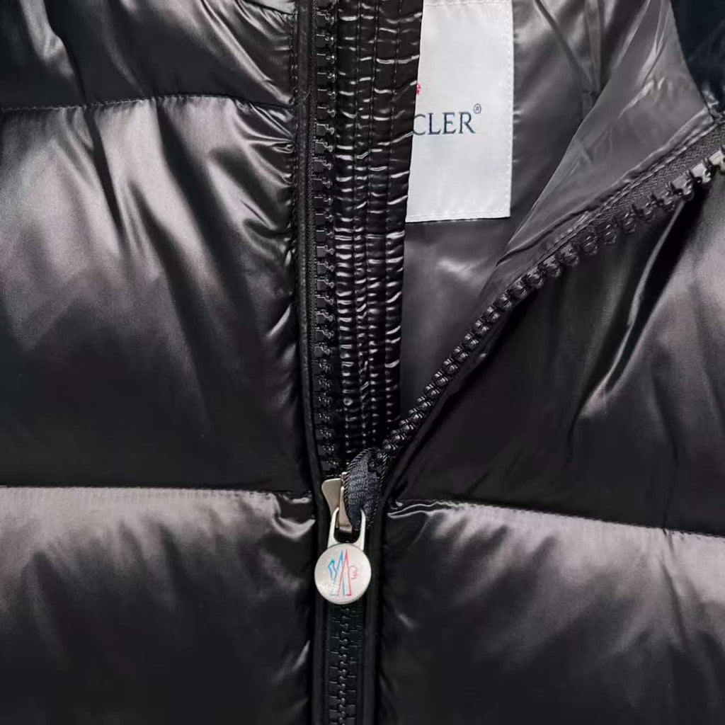Moncler puffer jacket close-up, dark color, full-zip front with metal zipper pull