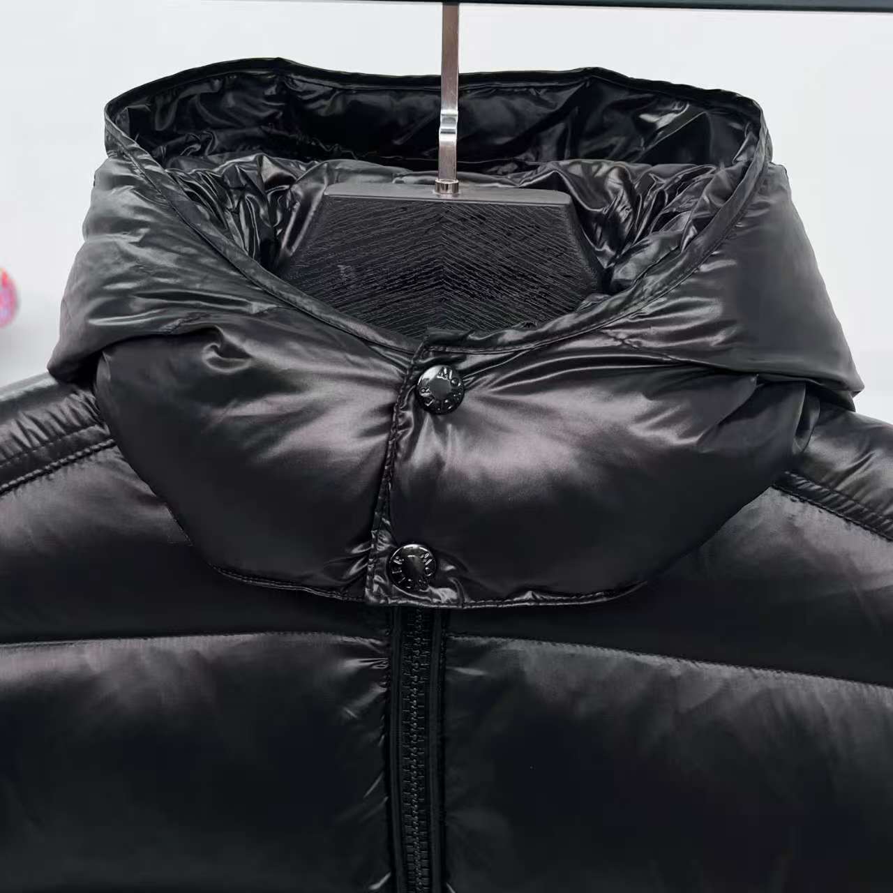 Moncler puffer jacket hooded inner layer close-up, dark color with snap buttons
