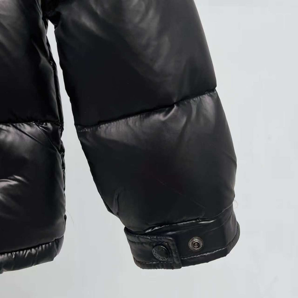 Moncler puffer jacket cuff close-up, dark color with snap button closure
