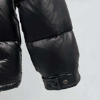 Moncler puffer jacket cuff close-up, dark color with snap button closure