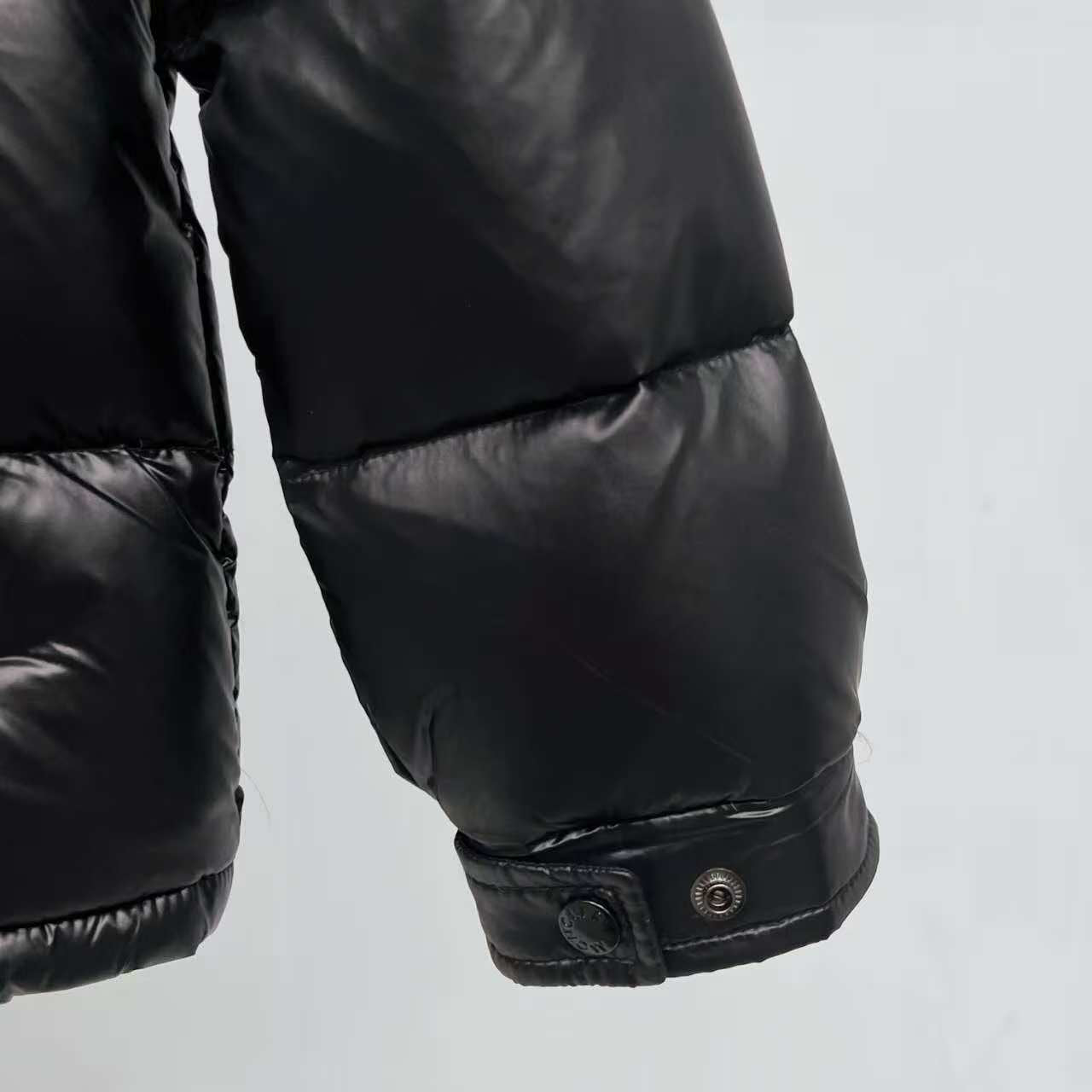 Moncler puffer jacket cuff close-up, dark color with snap button closure