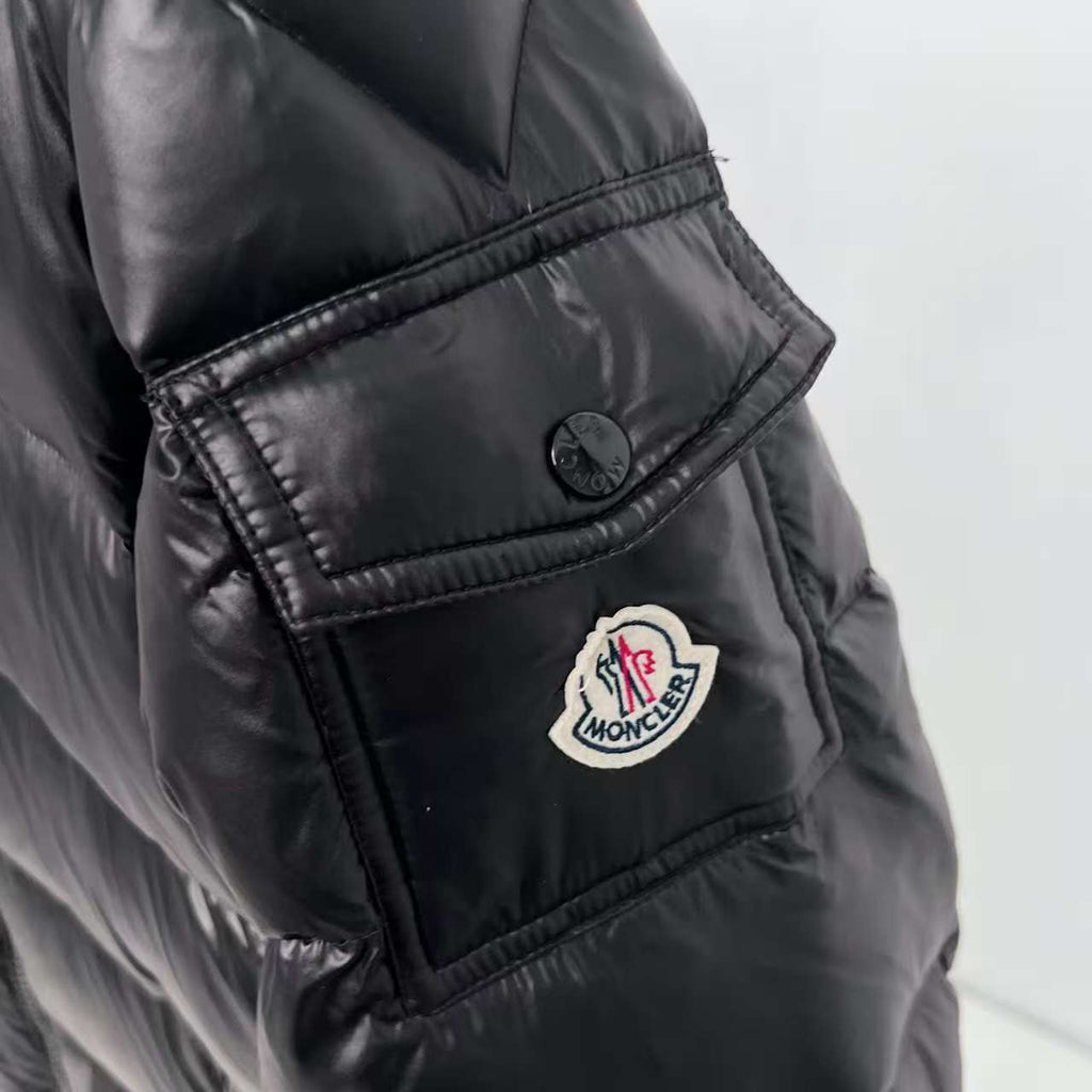 Moncler puffer jacket sleeve/side patch close-up, dark color with circular logo