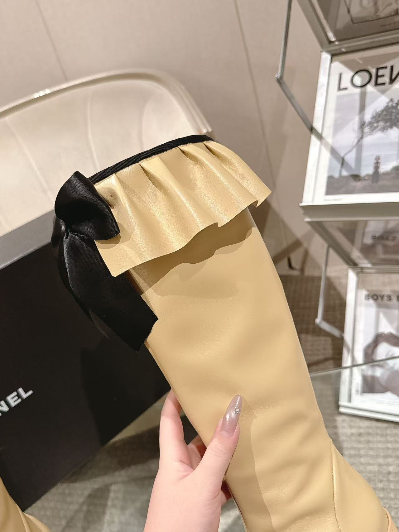 Chanel ladies’ knee-high boot detail with black bow and cream pleated top
