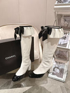 Chanel knee-high boots with black ribbon bows, white uppers and black glossy heels