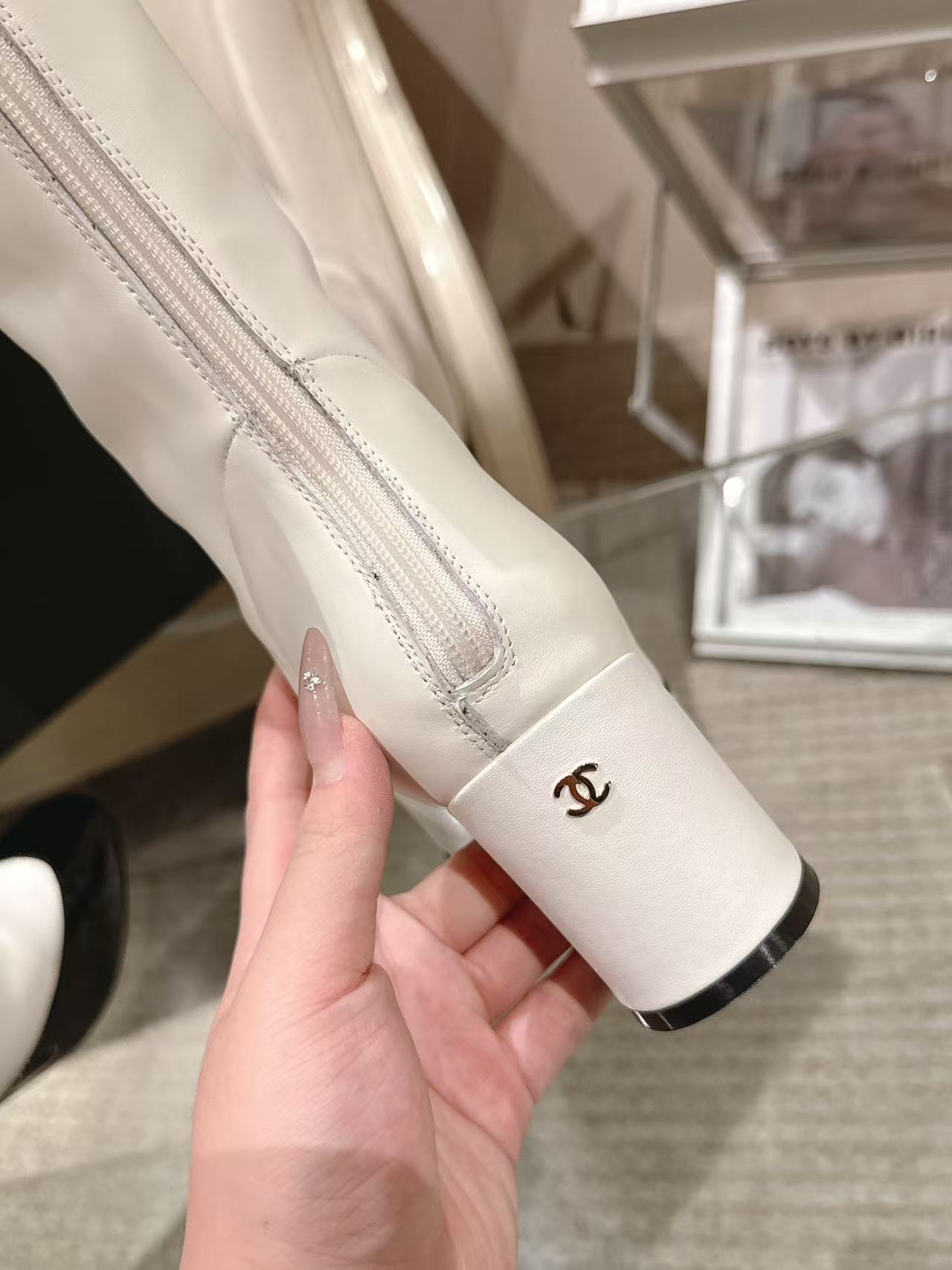 Chanel white leather boot shaft close-up with small logo near ankle