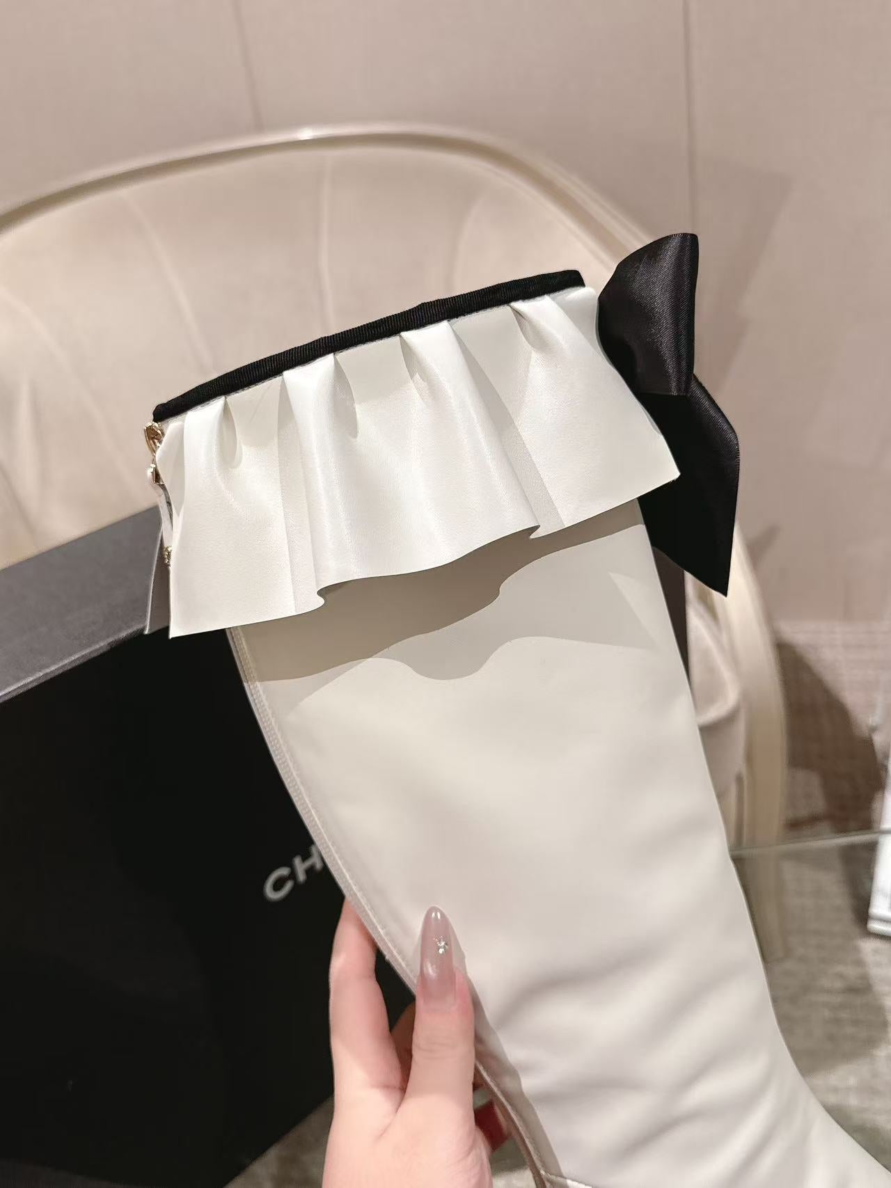 Chanel white knee-high boot with ruffled cuff and black ribbon bow at top