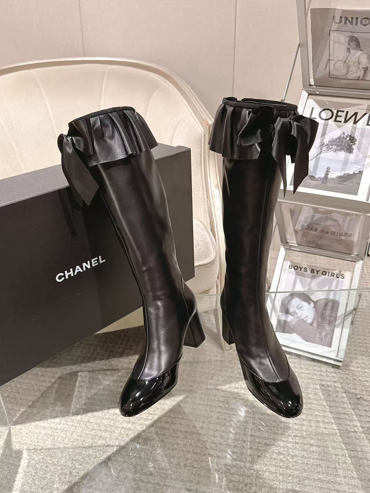 Black knee-high leather boots with bow trim and glossy toe