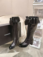 Black knee-high leather boots with wide ruffled bow detail