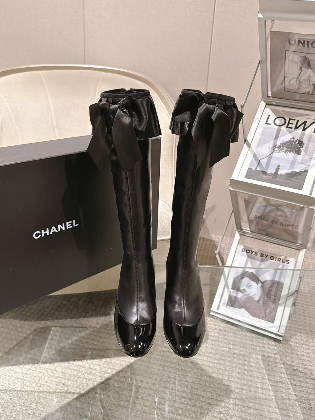 Pair of black knee-high leather boots with front bow accents