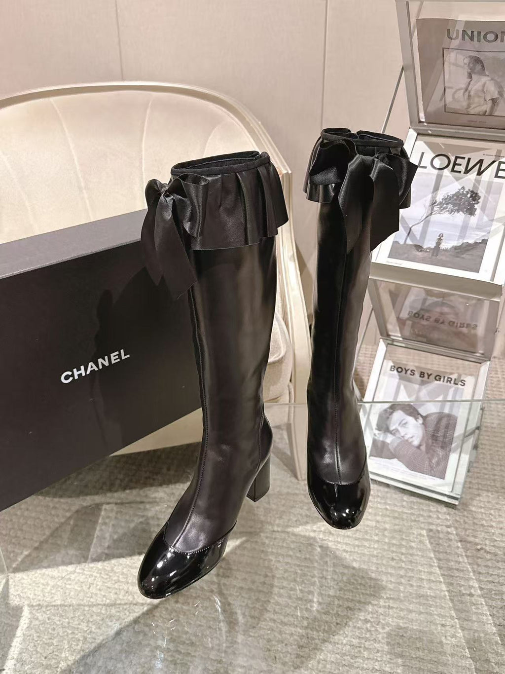 Black knee-high leather boots with ruffled bow at the ankle and block heel