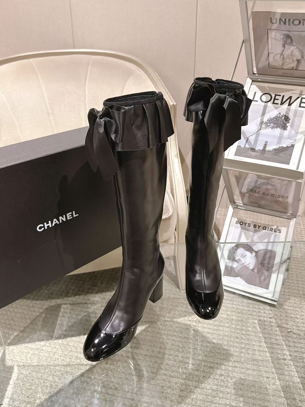 Black knee-high leather boots with ruffled bow at the ankle and block heel