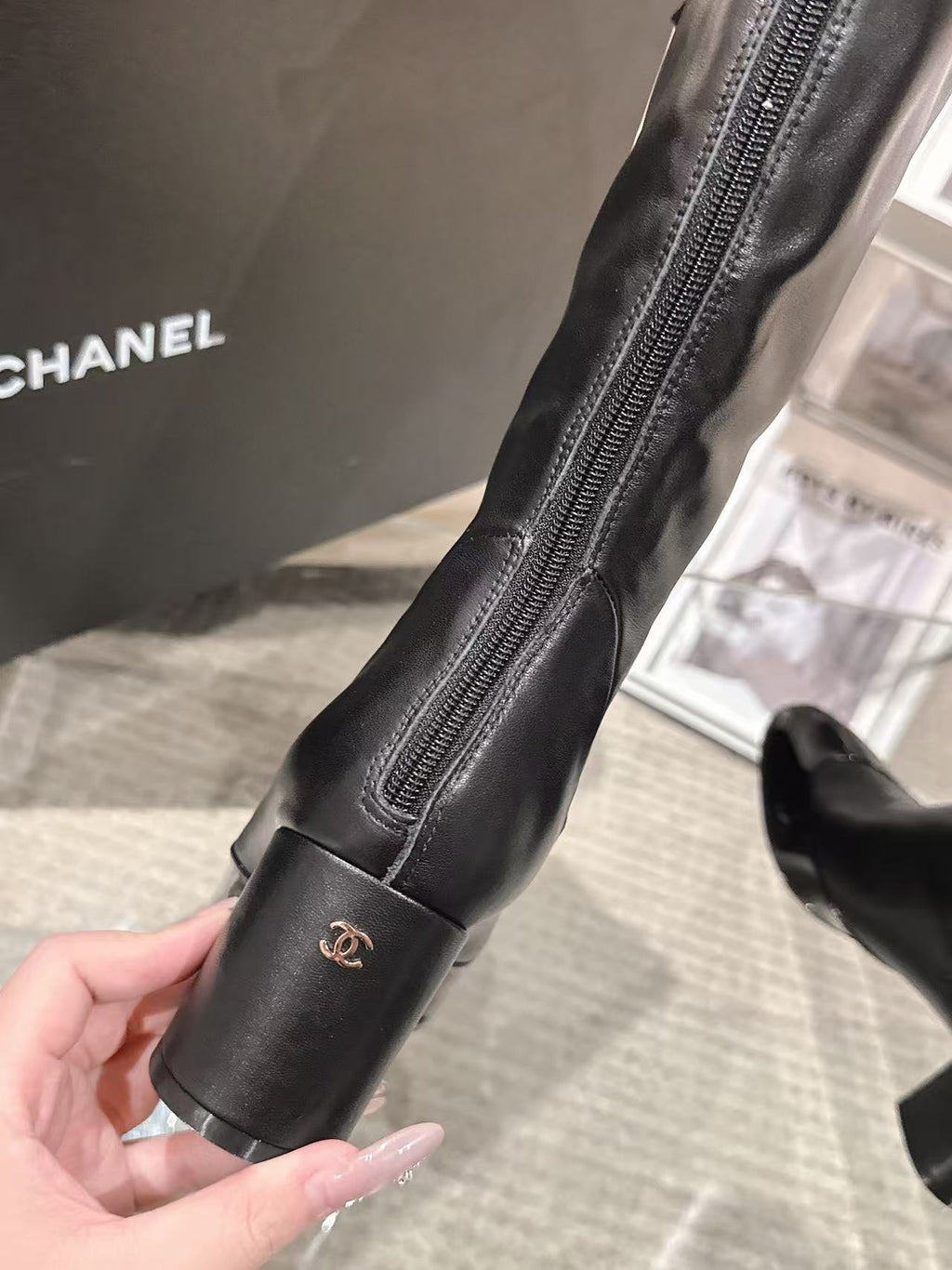 Black knee-high leather boot with side zipper and small logo near cuff