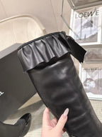 Black knee-high leather boot with gathered ruffle bow at the top