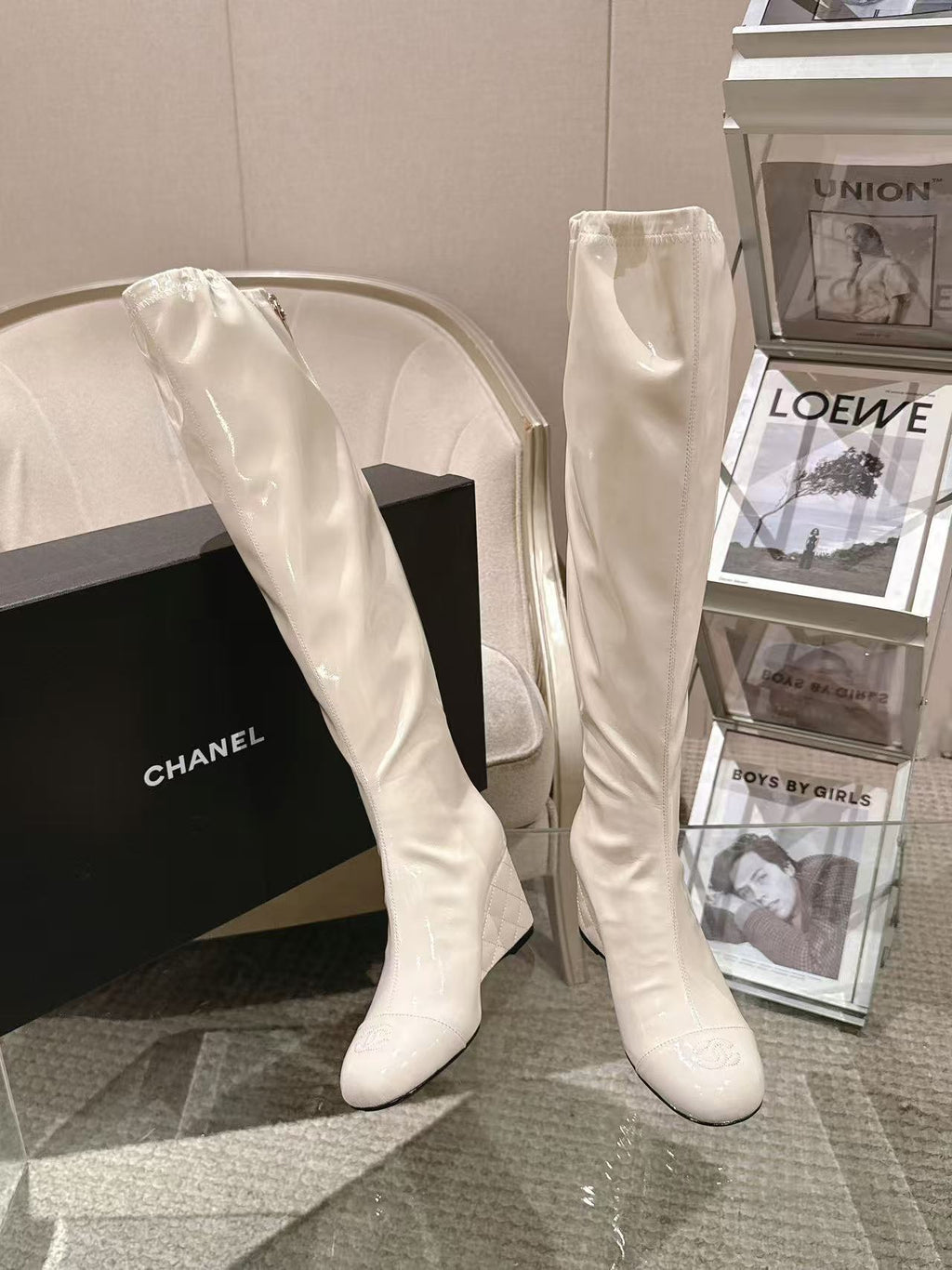 Chanel knee-high boots in light white patent leather, angled with pointed toe