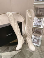 Chanel knee-high boots in light white patent leather, angled with pointed toe