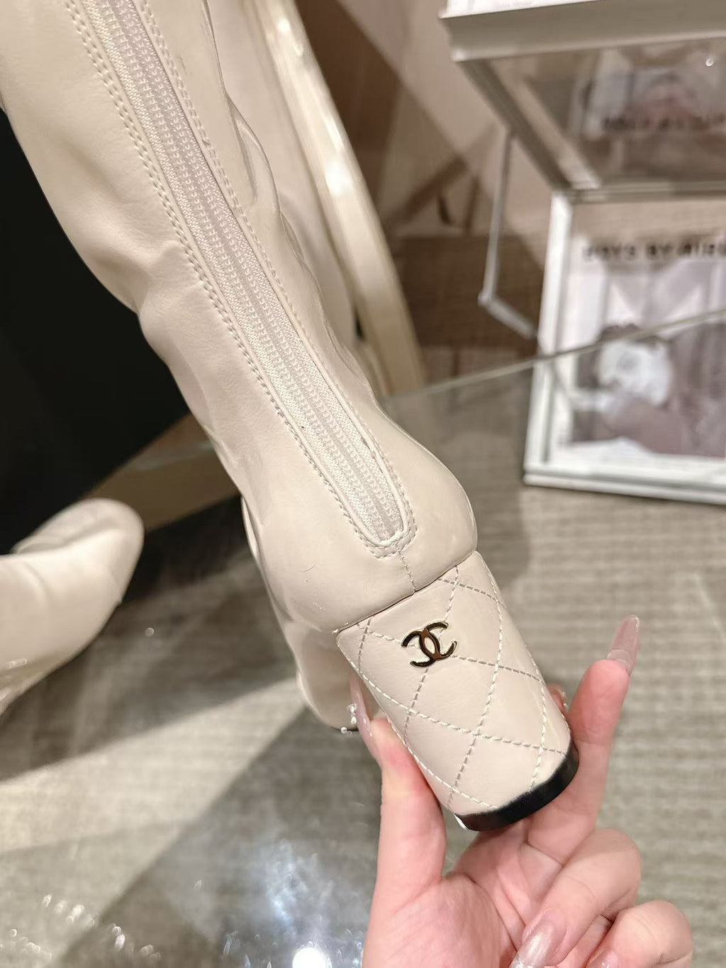Chanel knee-high boot instep detail with CC logo on light white leather