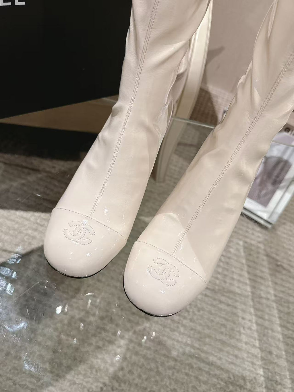 Pair of Chanel light white knee-high boots with embossed logo on toe