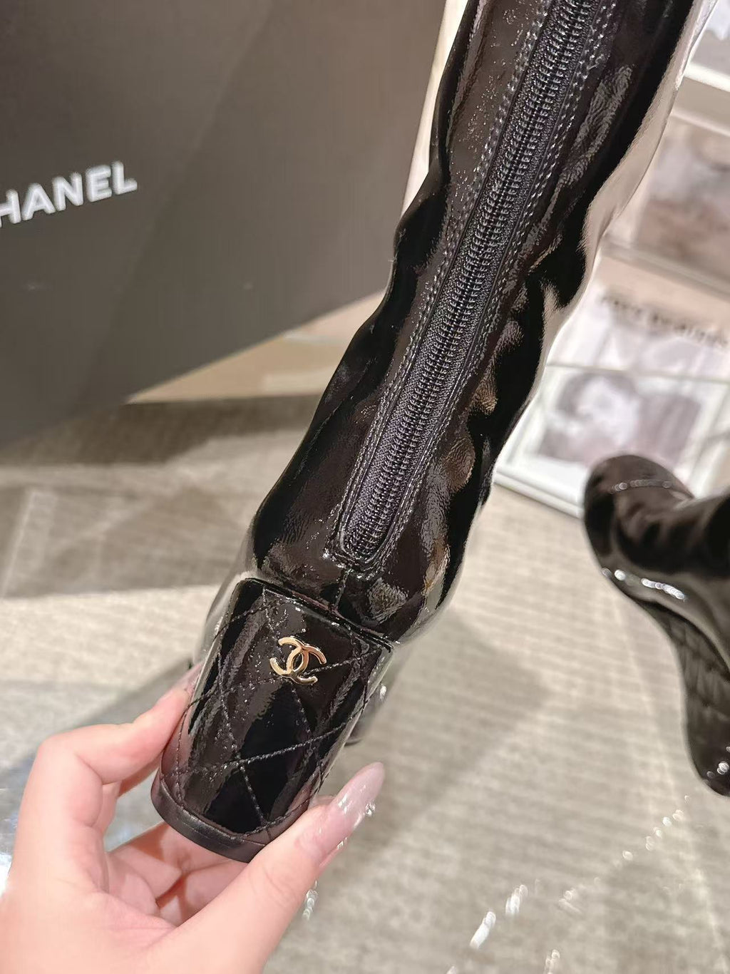 Chanel black patent leather knee-high boot, close-up of zipper and logo patch