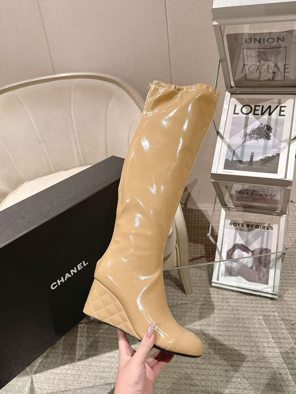 Chanel glossy beige knee-high boot with slim heel, hand-held close angle