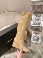 Chanel glossy beige knee-high boot with slim heel, hand-held close angle