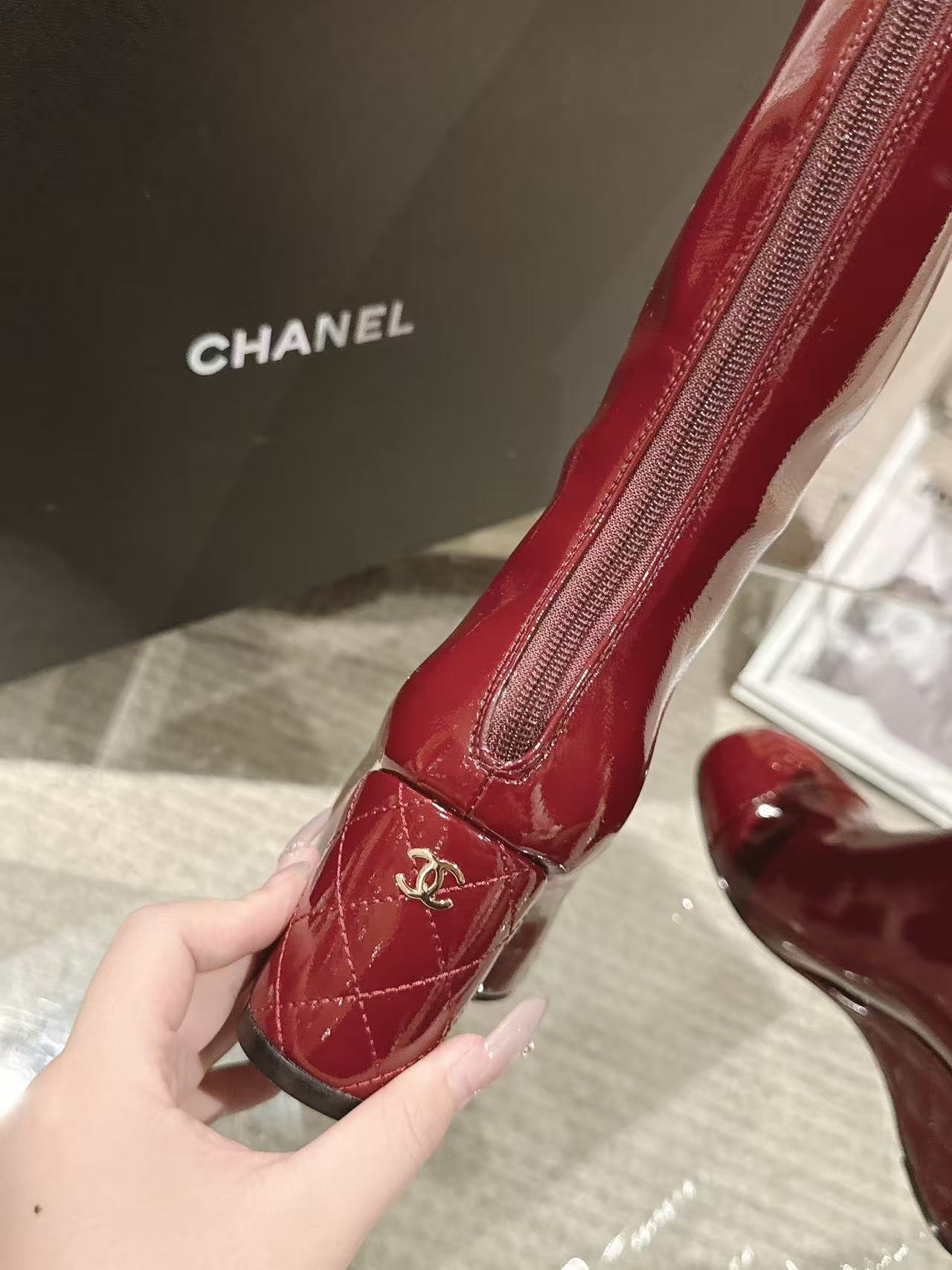 Red patent leather knee boot with zipper and Chanel logo patch