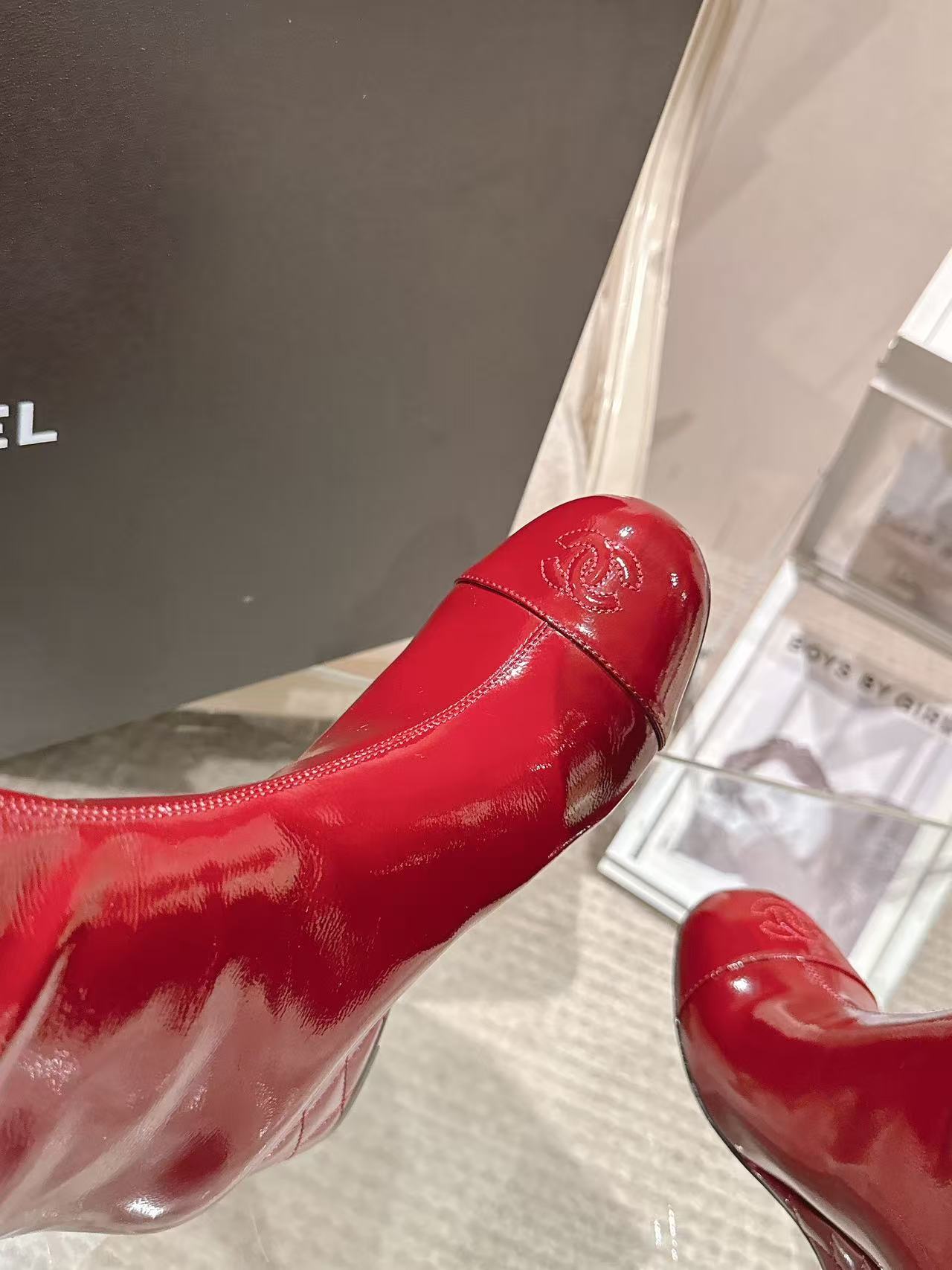 Red patent leather boot toe with Chanel logo and stitched detailing