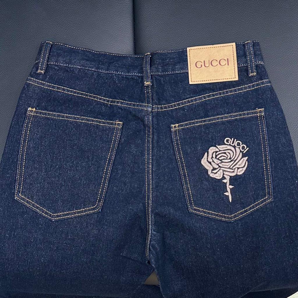 Dark blue denim jeans with rose embroidered back pockets and GUCCI waistband tab