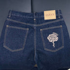 Dark blue denim jeans with rose embroidered back pockets and GUCCI waistband tab