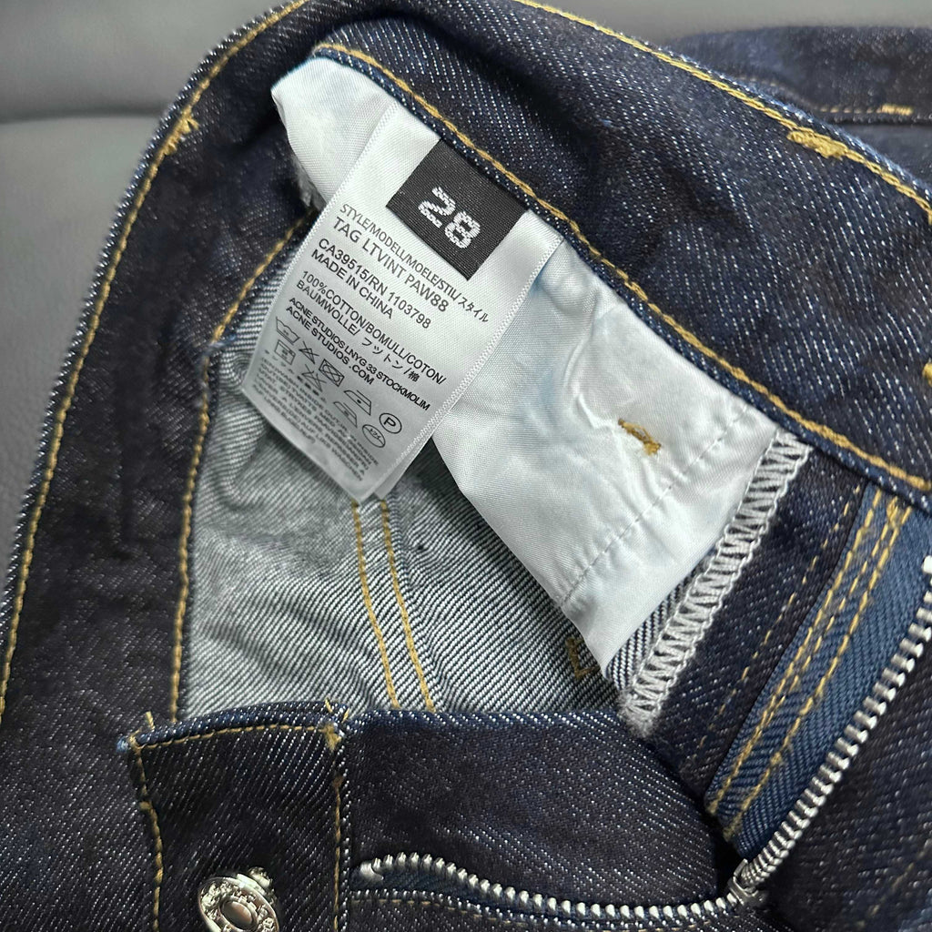 Inside label and waistband seam detail on dark blue denim jeans