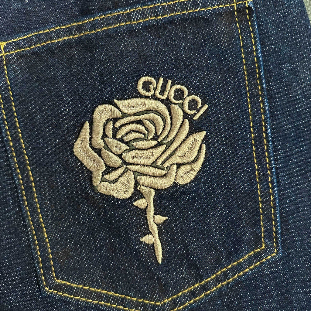 Close-up of rose and GUCCI embroidery on denim back pocket