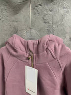 Pink hoodie front close-up with hood, zipper, and white brand tag