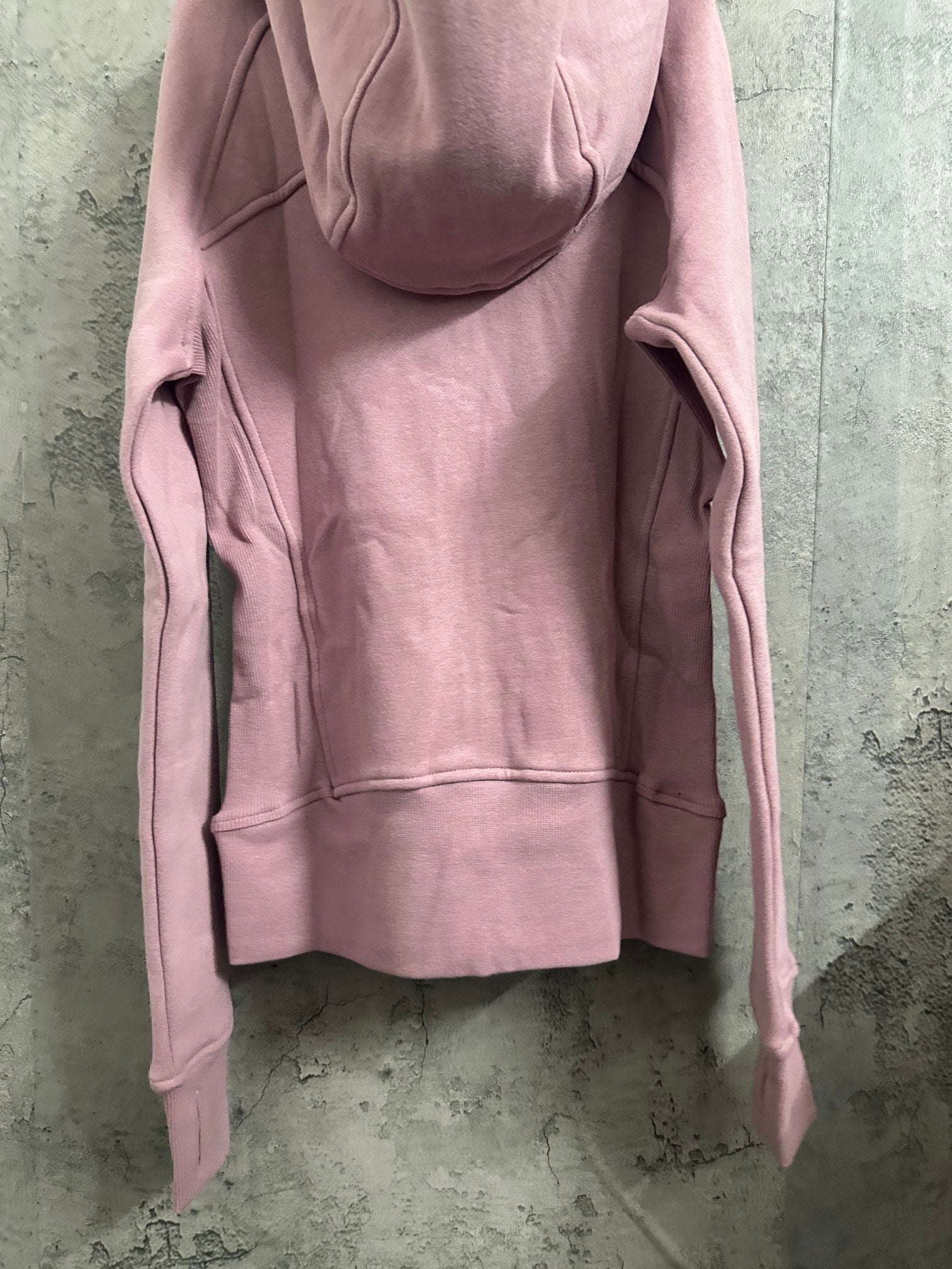 Pink zip-up hoodie back view with hood and front hem seams
