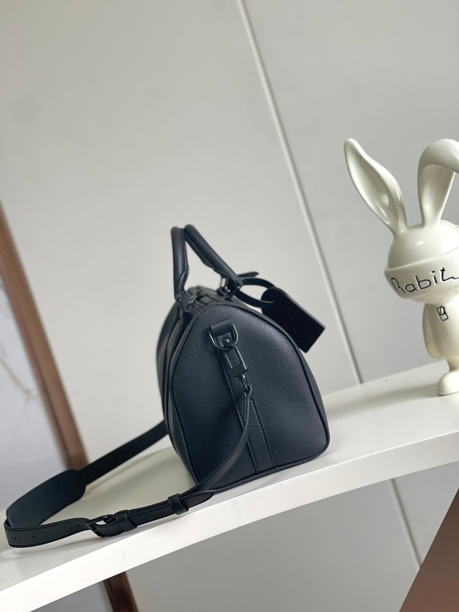 Louis Vuitton barrel bag with crossbody strap and structured front buckle detail