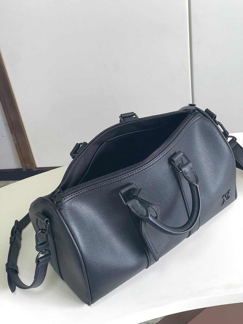 Louis Vuitton small duffel bag with zipper top, side handles, and shoulder strap