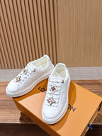 White Louis Vuitton sneakers on box, lace-up with gold charm accents